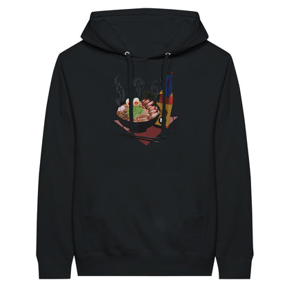 Black premium hoodie featuring a print of a steaming bowl of ramen with eggs, seaweed, and slices of meat, accompanied by a bottle of sake and chopsticks, set on a red geometric background.